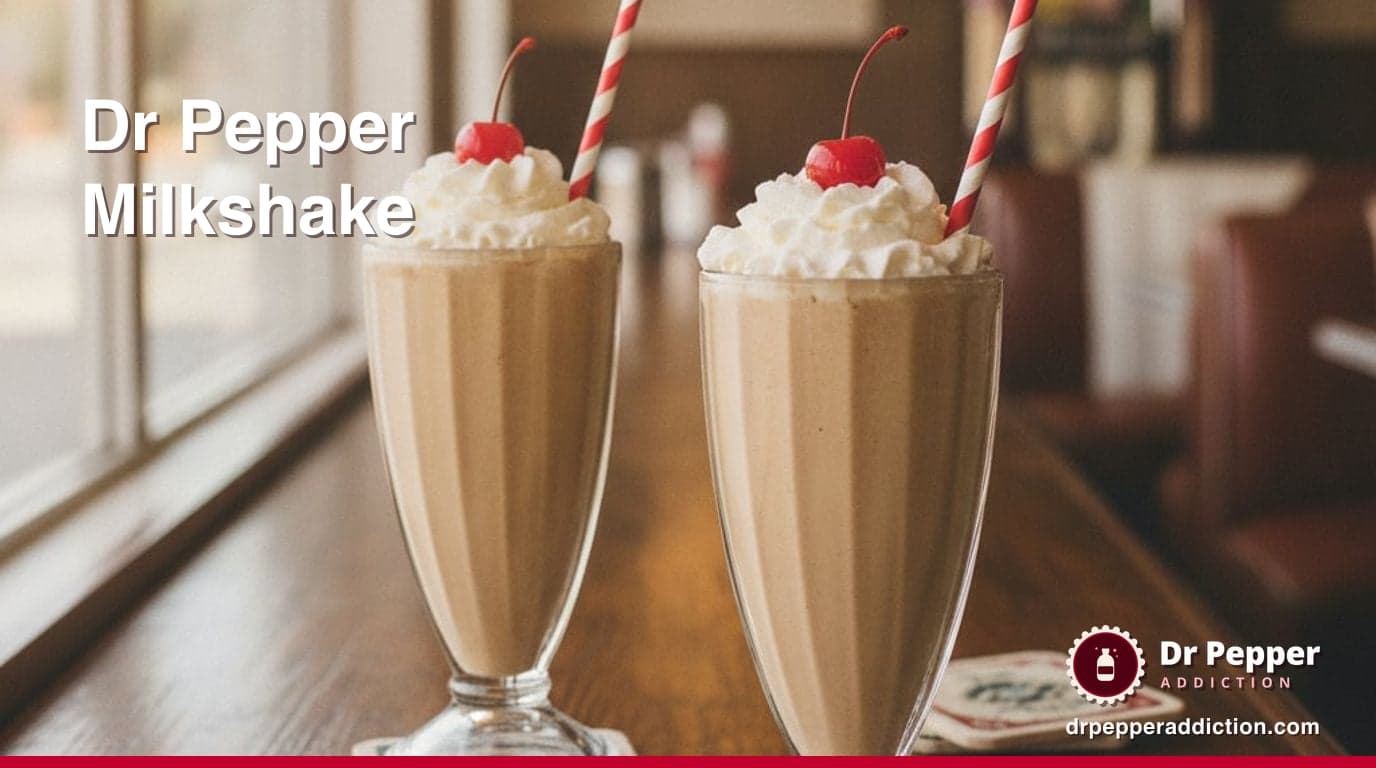 Two tall glasses of thick, light caramel-brown milkshake topped with whipped cream and a red cherry, with straws, on a diner-style counter